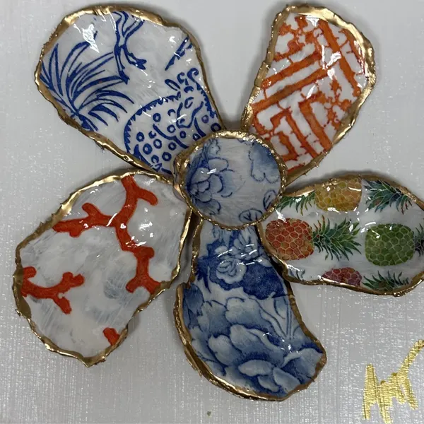 A six-petal shell flower wall art with a blue vase motif, coral branches, and pineapple pattern around a blue floral center.