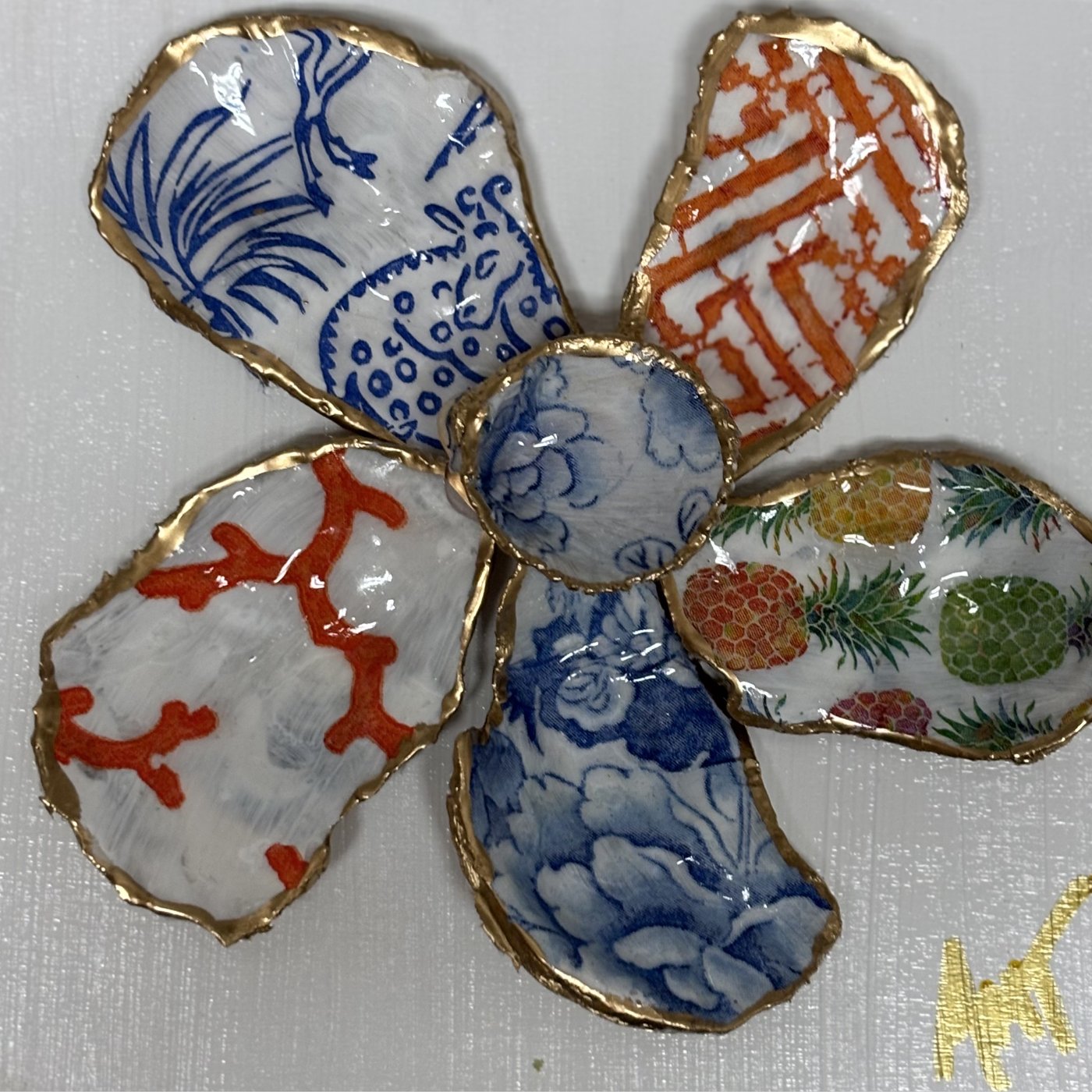 A six-petal shell flower wall art with a blue vase motif, coral branches, and pineapple pattern around a blue floral center.
