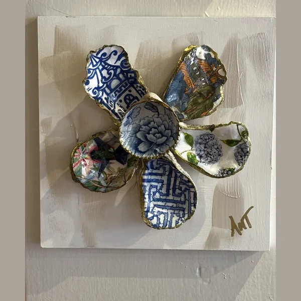 A six-petal shell flower wall art with blue and white chinoiserie and floral patterns around a blue floral center.