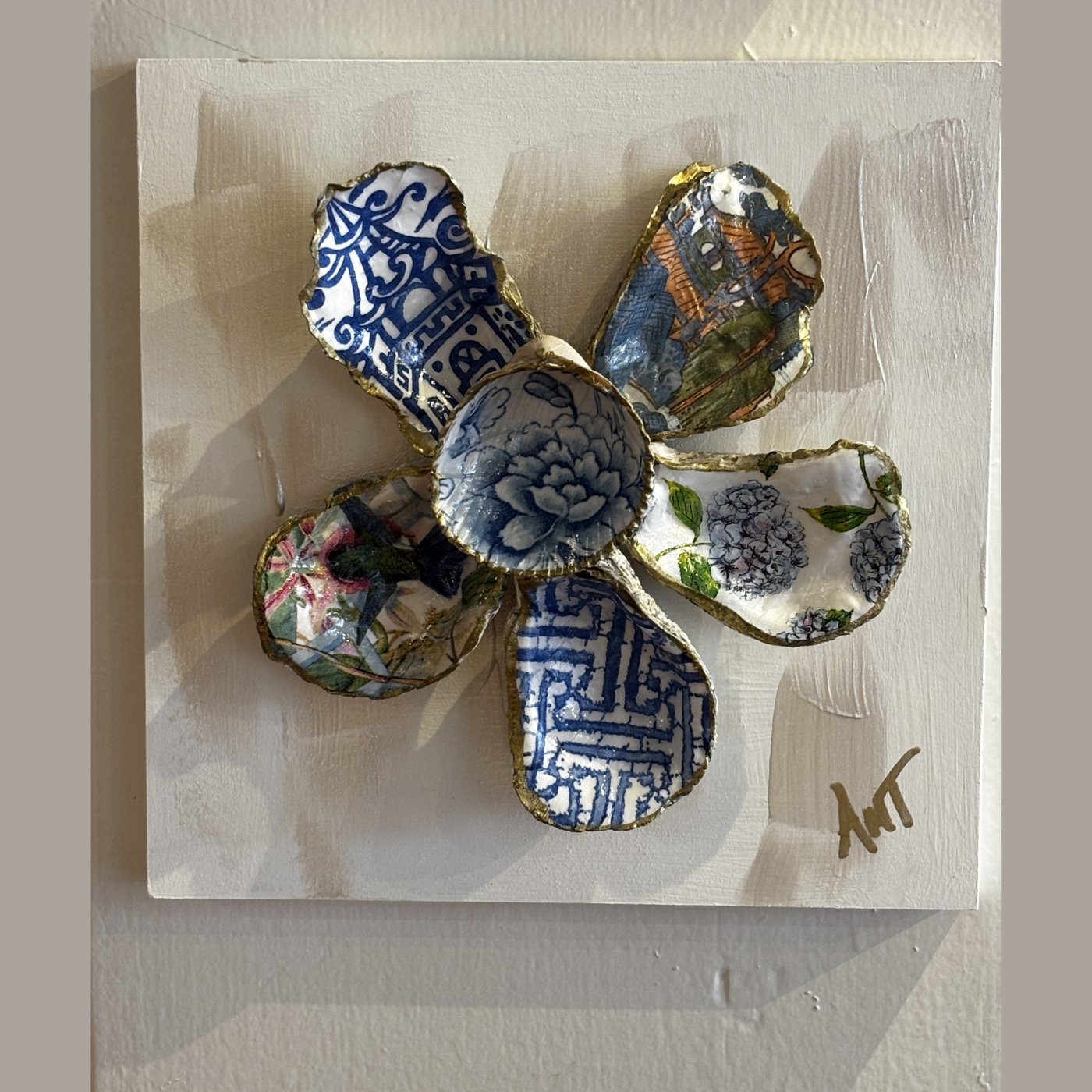 A six-petal shell flower wall art with blue and white chinoiserie and floral patterns around a blue floral center.