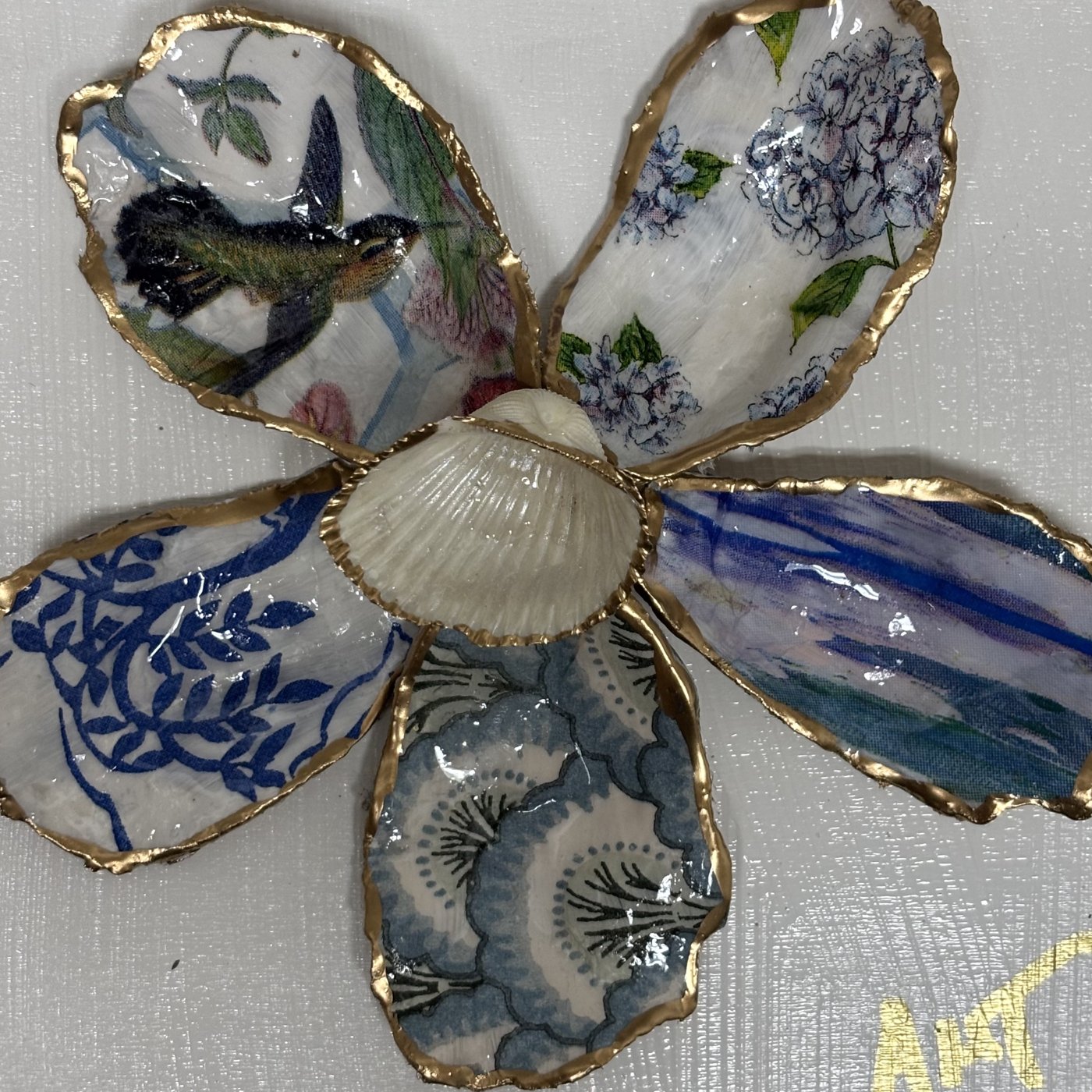 A six-petal shell flower wall art with hydrangea, hummingbird, and chinoiserie patterns around a pearl center.