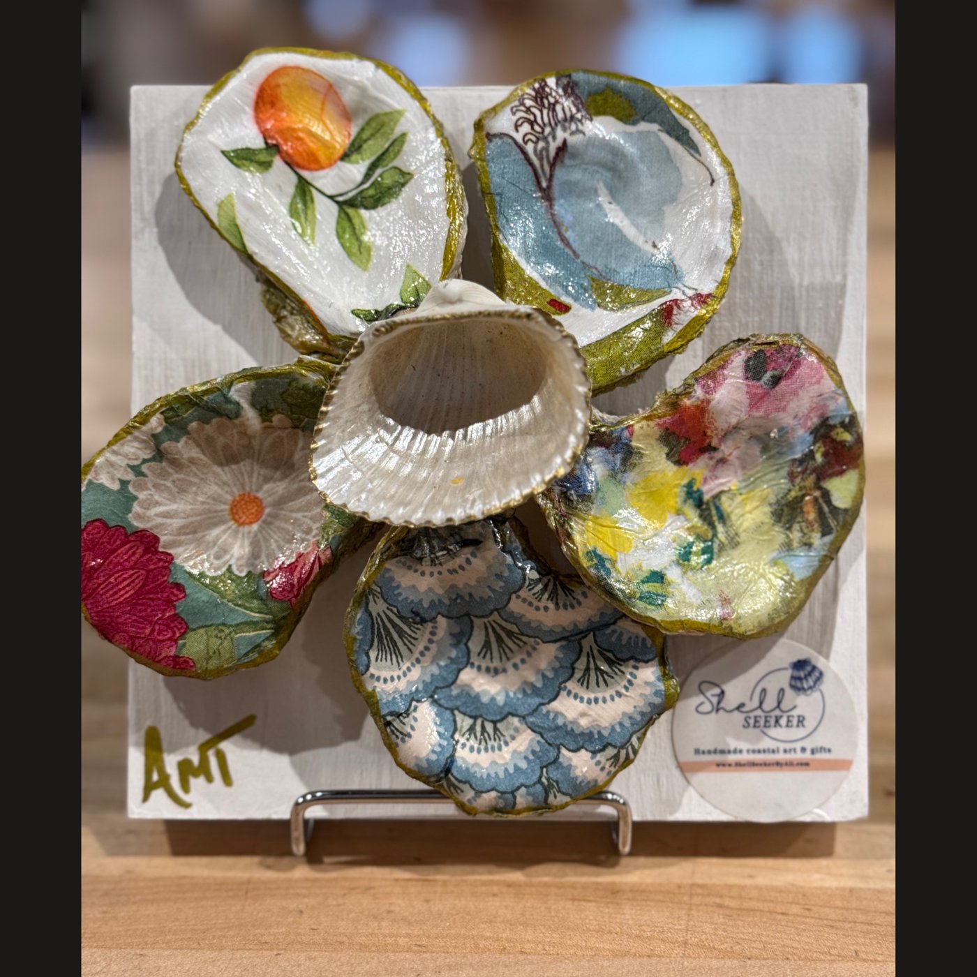 A six-petal shell flower wall art mixing citrus, floral, and teal watercolor patterns around a pearl center.