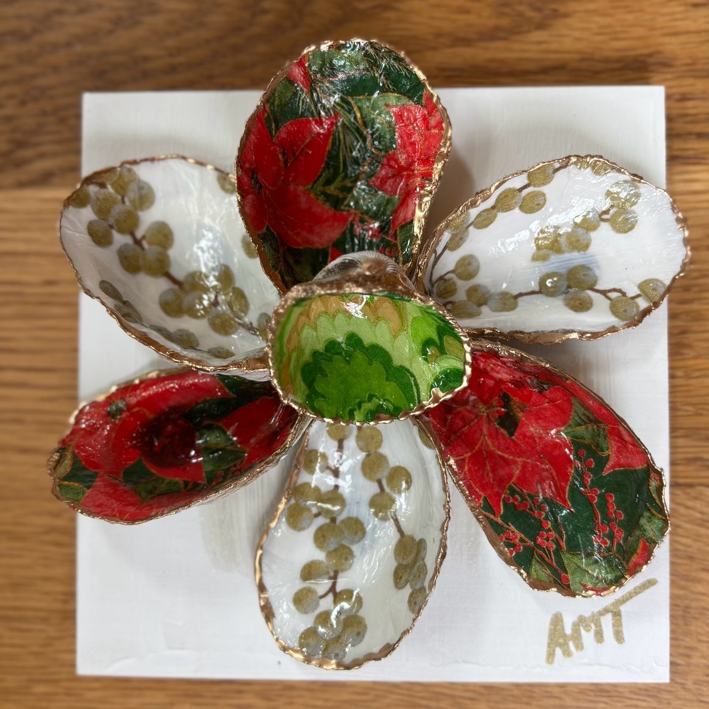 A six-petal Christmas shell flower wall art alternating red poinsettia and gold berry petals around a green center.