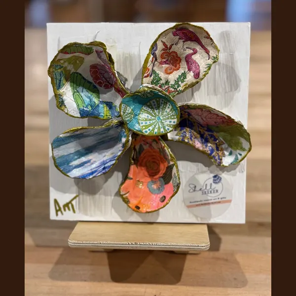 A six-petal shell flower wall art with rose, teal swirl, and floral patterns around a sea urchin center.