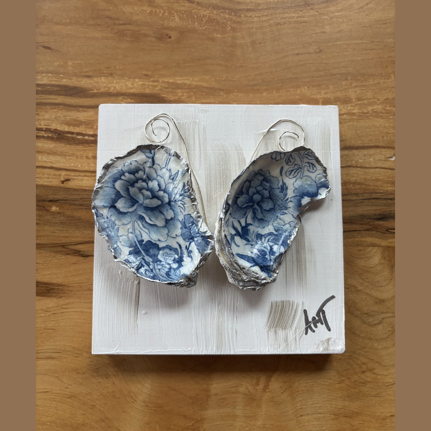 Two oyster shells forming a heart, decorated in a blue and white floral toile pattern.