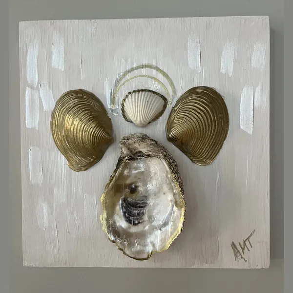 A wood panel angel made from gilded clam shells and an oyster shell body.