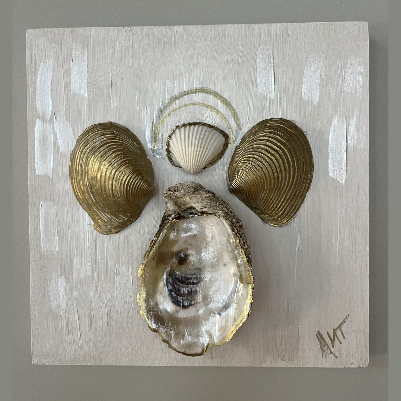 A wood panel angel made from gilded clam shells and an oyster shell body.