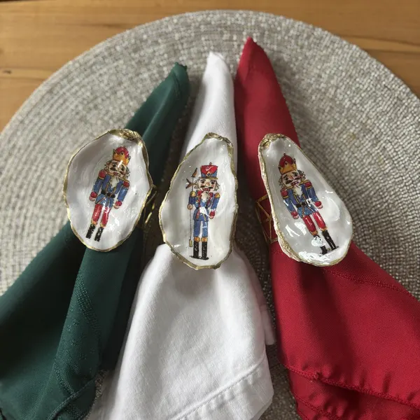 Gold-rimmed oyster shell napkin rings with a classic red and blue nutcracker soldier.