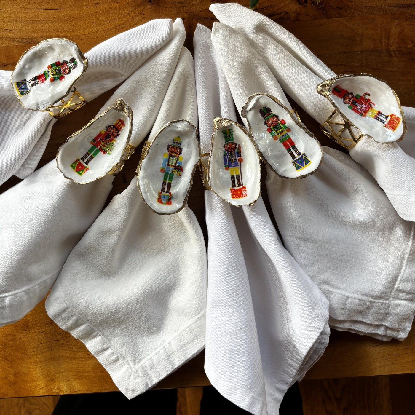 Gold-rimmed oyster shell napkin rings with colorful nutcracker soldiers and their drums, each one a little different.