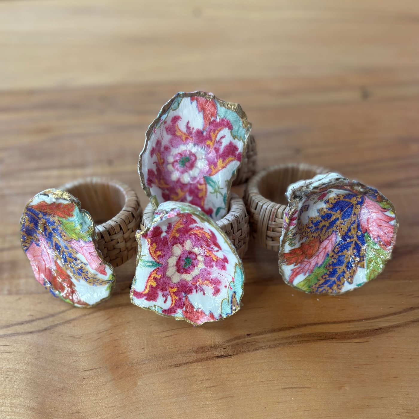 Gold-rimmed shell napkin rings in a bright pink tobacco leaf pattern.