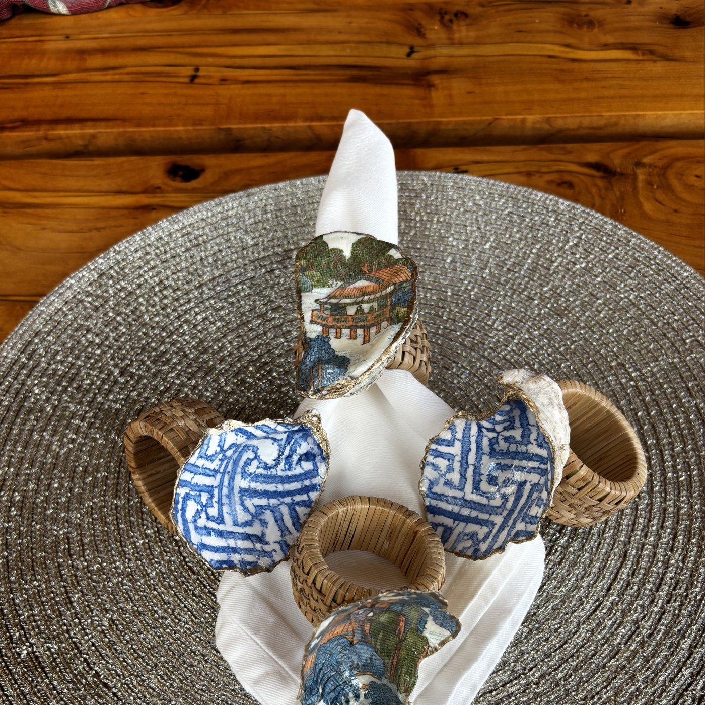 Gold-rimmed shell napkin rings in a mixed set of blue and white chinoiserie lattice and pagoda patterns.