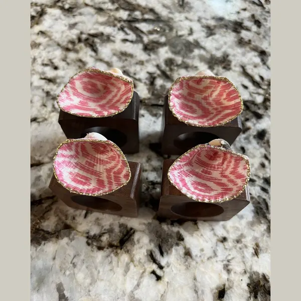 Gold-rimmed shell napkin rings in a pink ikat pattern.