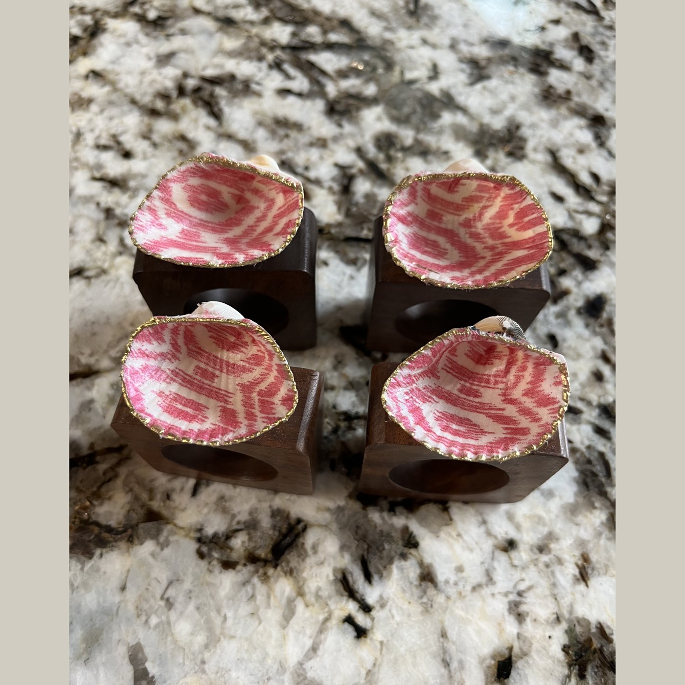 Gold-rimmed shell napkin rings in a pink ikat pattern.