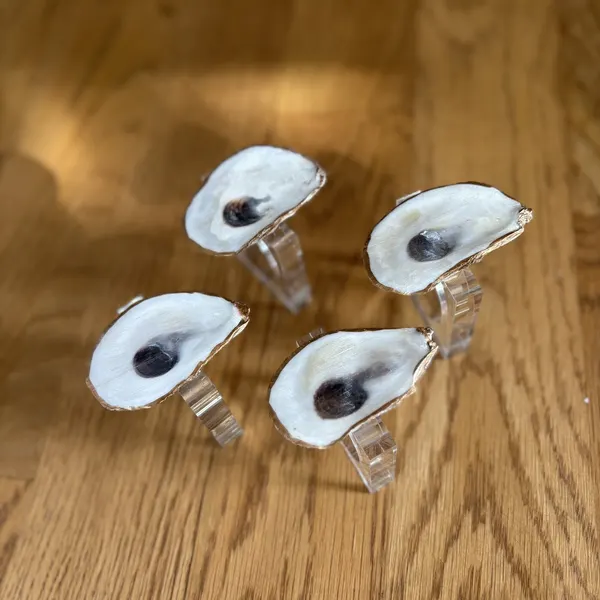 Gold-rimmed oyster shell napkin rings with a bright white pearlized finish.