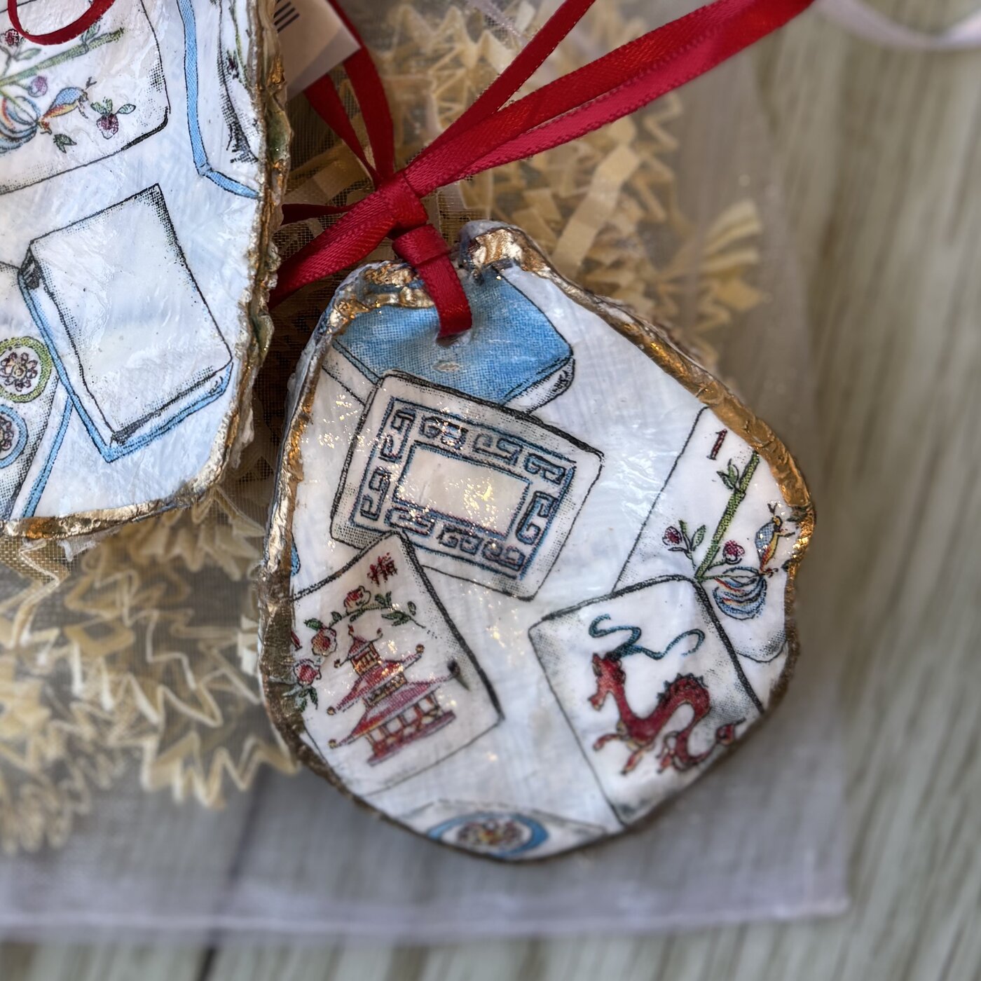 An oyster shell ornament covered in mahjong tiles. Each one shows a different mix of tiles. Comes in a gift bag.