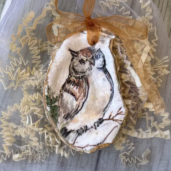 A gold-rimmed oyster shell ornament with an owl perched on a winter branch. Comes in a gift bag.