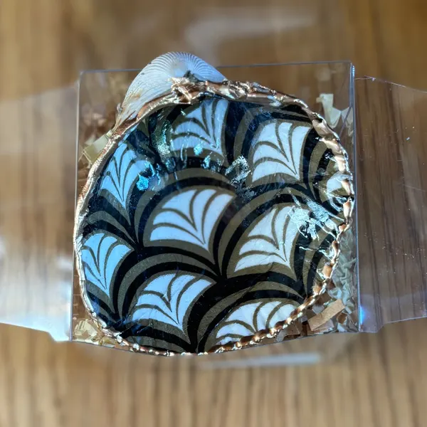 A gold-rimmed shell ring dish with an Art Deco black, gold and white fan pattern. Comes in a gift box.