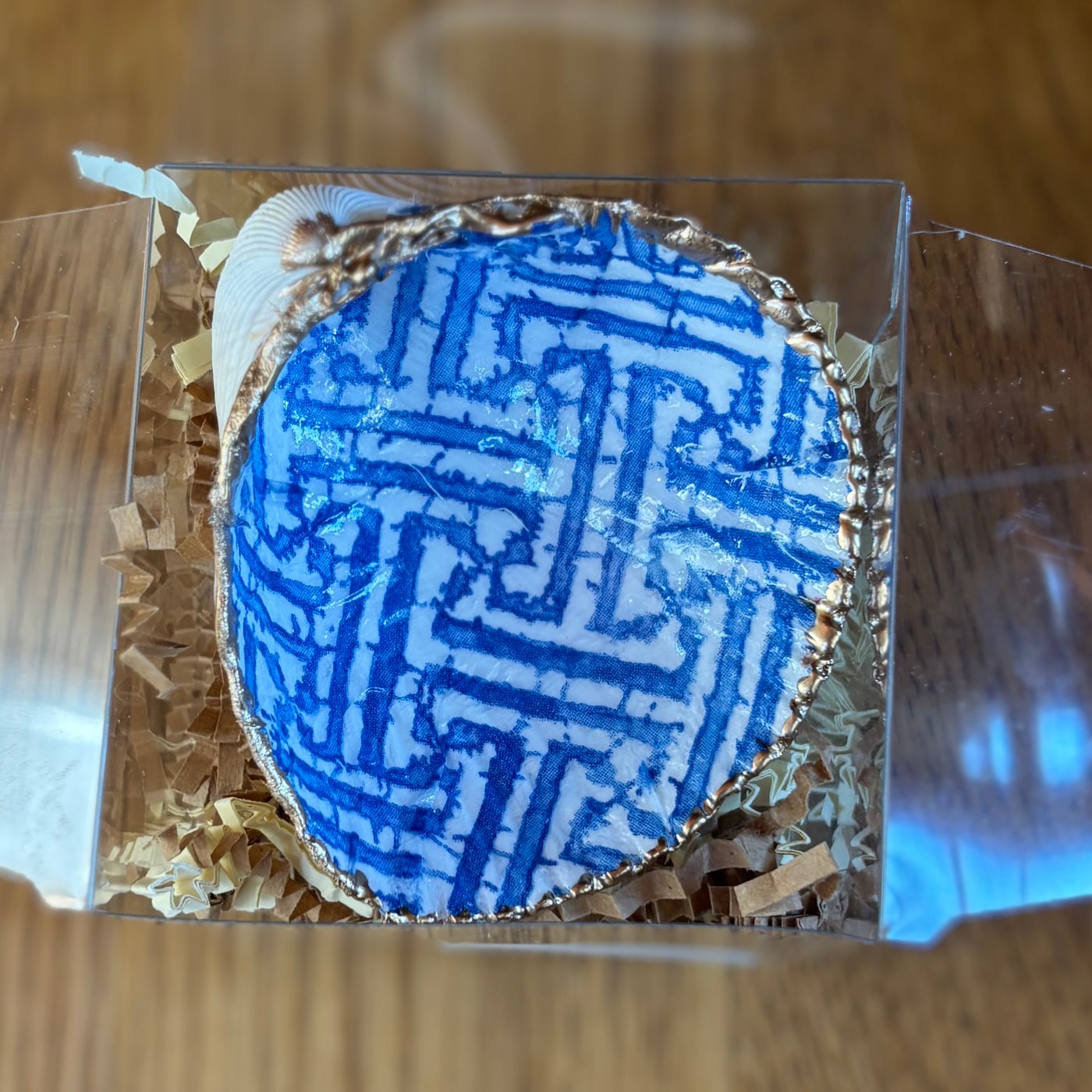 A gold-rimmed shell ring dish with a blue and white chinoiserie lattice pattern. Comes in a gift box.