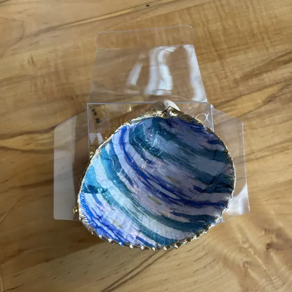 A gold-rimmed shell ring dish with a blue, teal, and purple swirl design. Comes in a gift box.