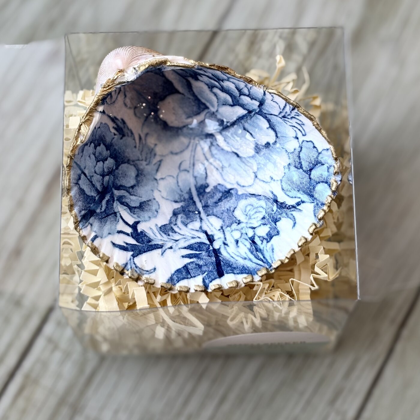 A gold-rimmed shell ring dish in a blue and white toile floral. Comes in a gift box.