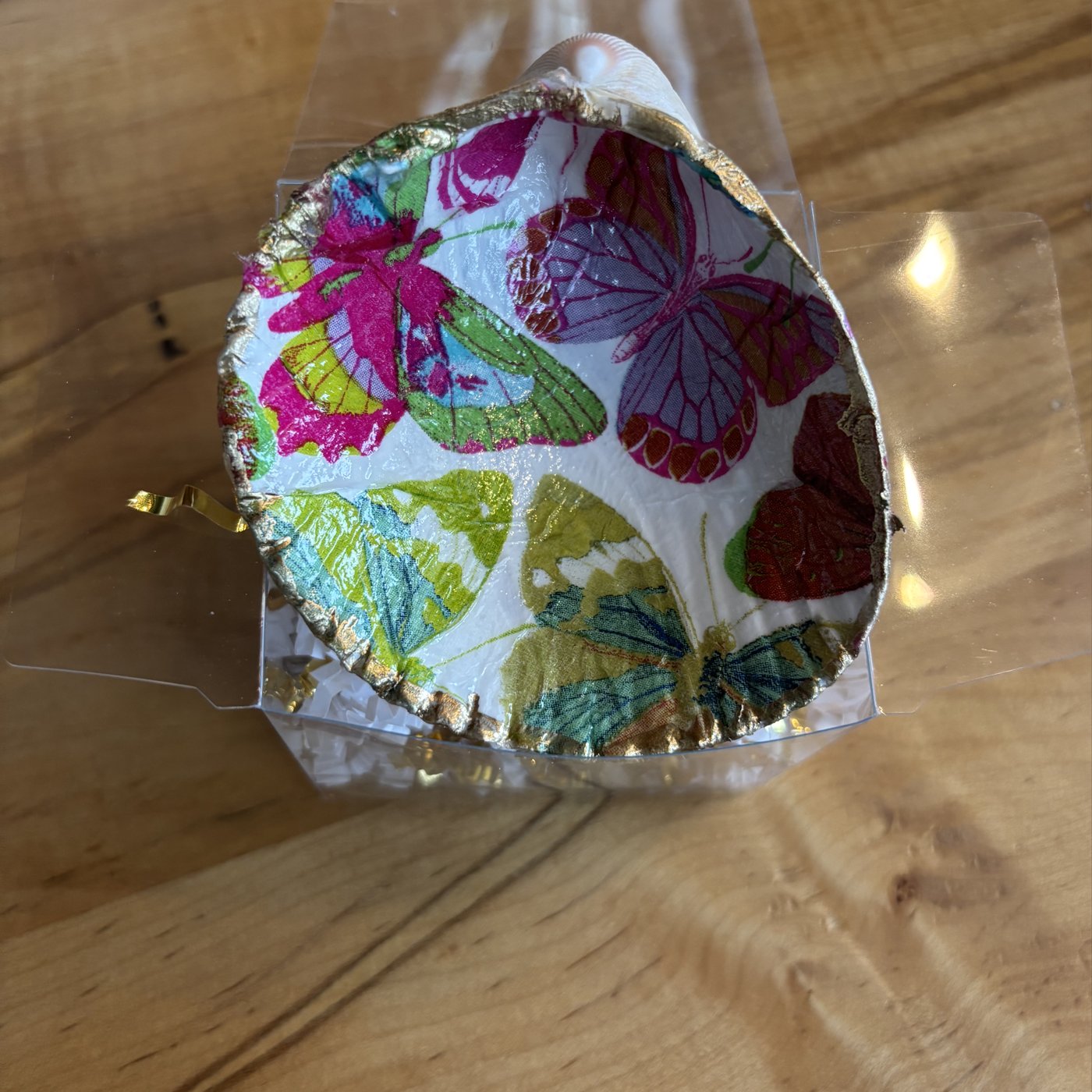 A gold-rimmed shell ring dish decorated with colorful butterflies. Comes in a gift box.