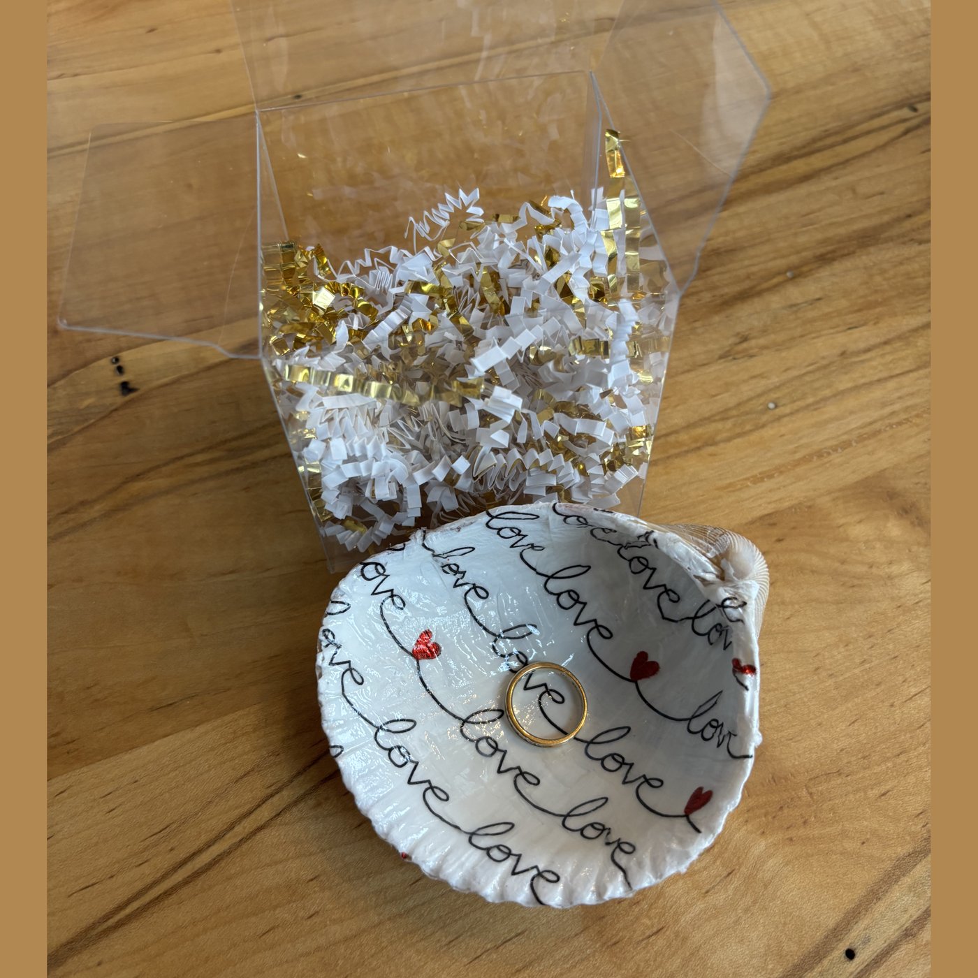A shell ring dish hand-lettered with "love" script and tiny hearts. Comes in a gift box.