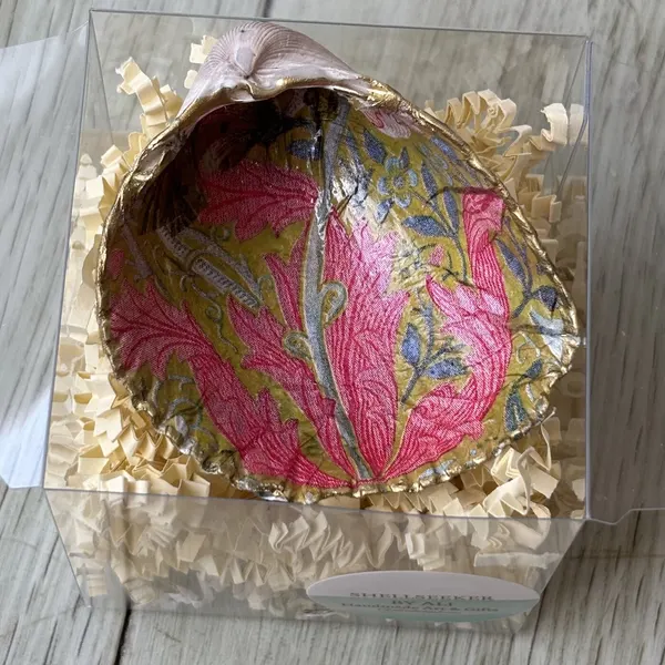 A gold-rimmed shell ring dish in a pink coral and olive leaf pattern. Comes in a gift box.