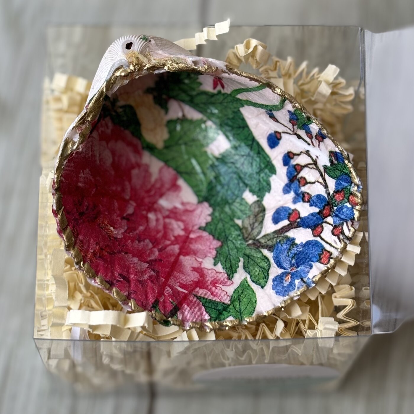 A gold-rimmed shell ring dish with a red peony and blue floral pattern. Comes in a gift box.