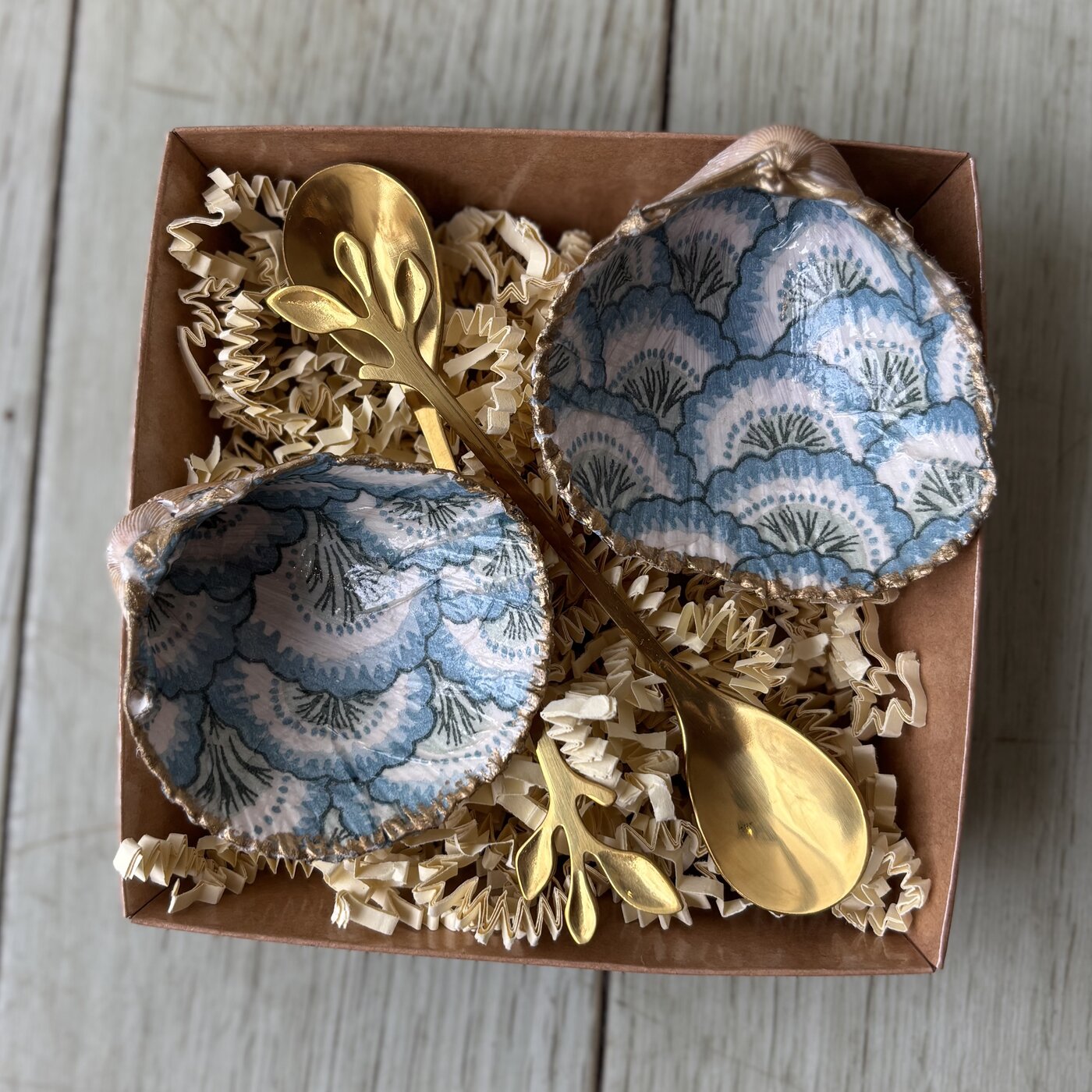 A pair of shell cellars covered in a blue and white fan pattern, gold-rimmed, with two gold or wooden spoons. Comes in a gift box.