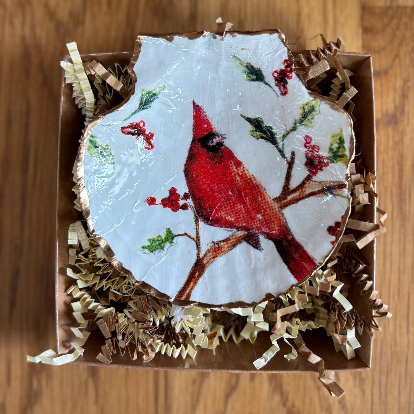 A scalloped shell dish featuring a cardinal and winter berries, gift-boxed.