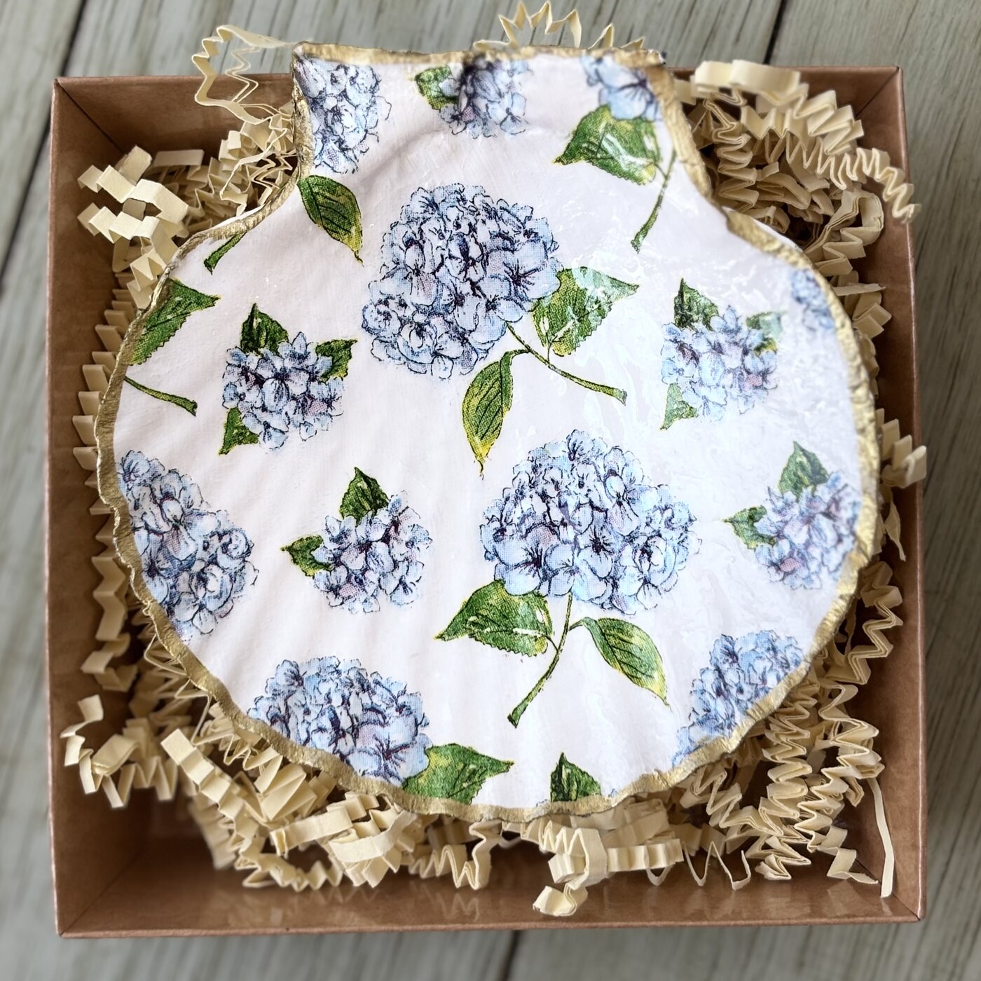 A shell dish decorated with blue hydrangea blooms, gift-boxed.
