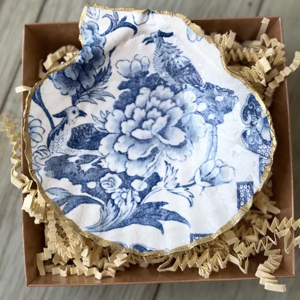 A gold-rimmed shell dish in a blue and white toile floral. Comes in a gift box.