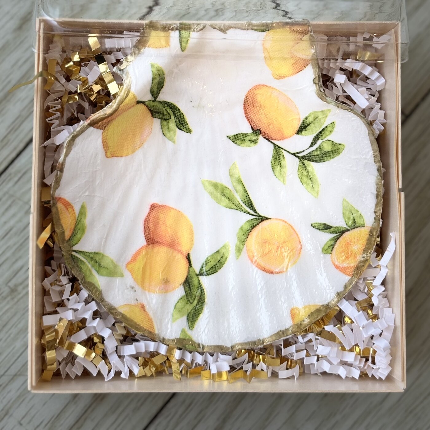 A gold-rimmed shell dish with lemons and oranges on the branch. Comes in a gift box.