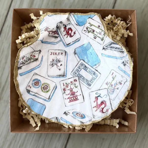A gold-rimmed shell dish patterned with mahjong tiles and playing cards. Comes in a gift box.