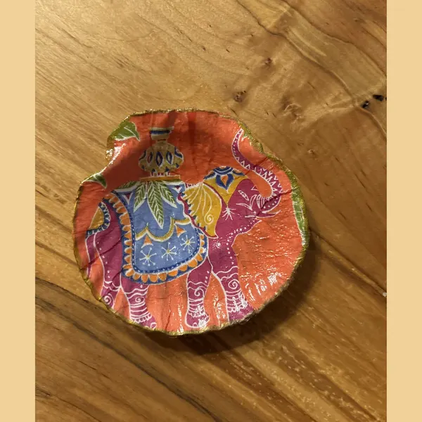 A shell dish decorated with a colorful patterned elephant. Comes in a gift box.