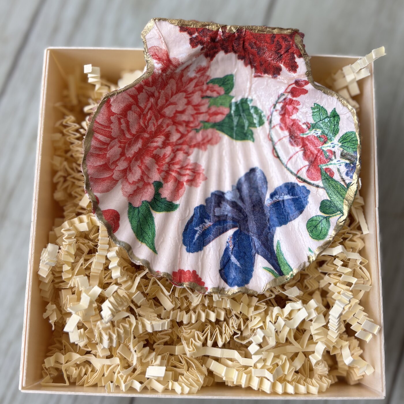 A gold-rimmed shell dish with a pink and red floral pattern, gift-boxed.