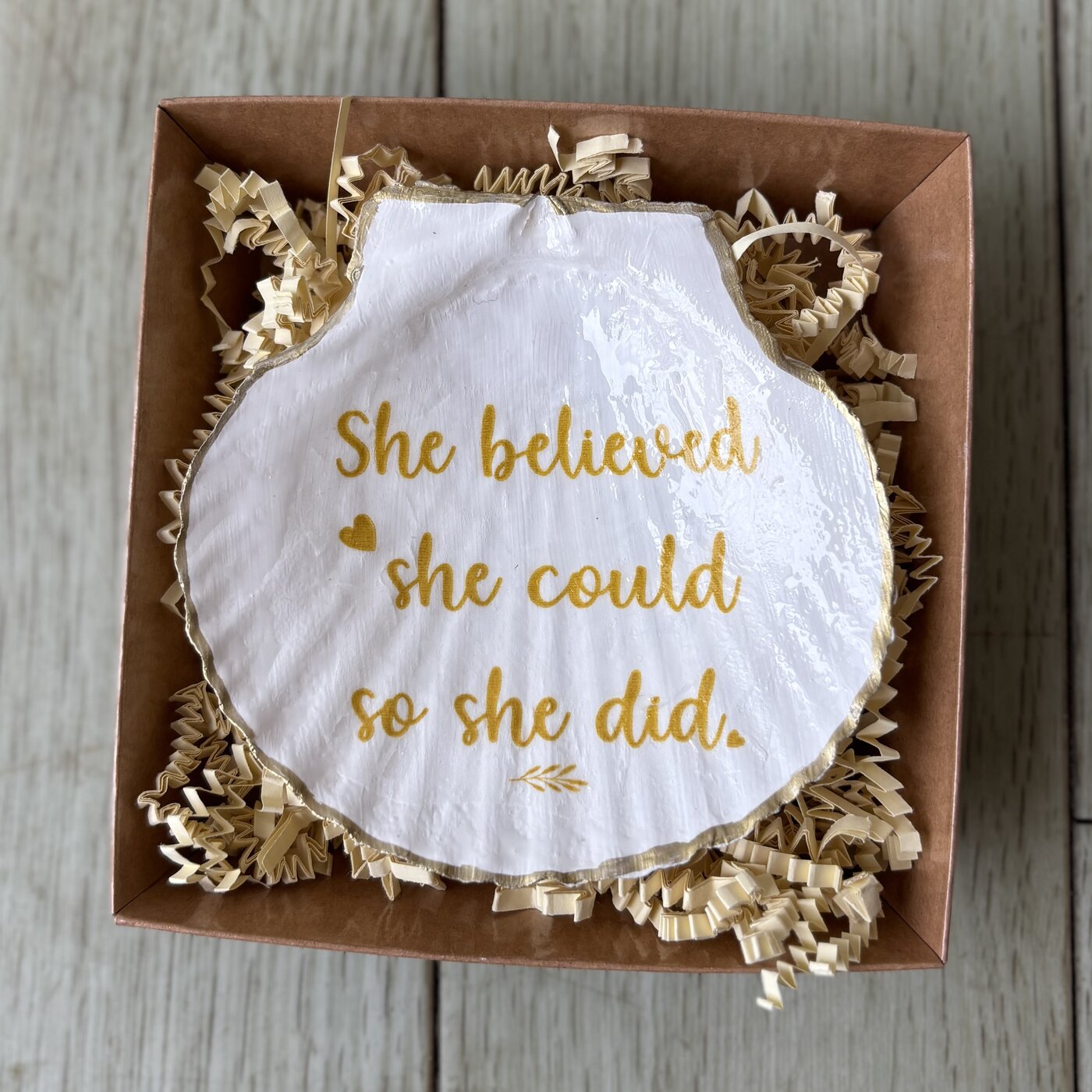 A shell dish hand-lettered in gold with "She believed she could so she did." Comes in a gift box.
