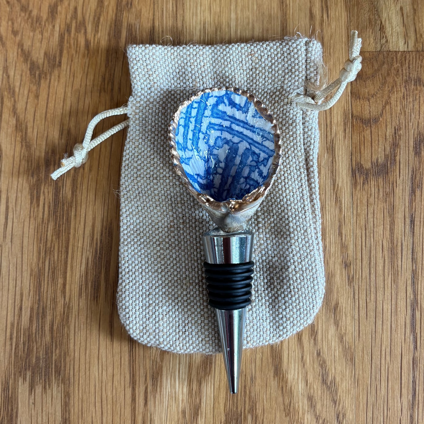 A wine bottle stopper topped with a shell in a blue and white chinoiserie lattice pattern.