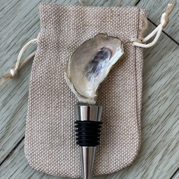 A wine bottle stopper topped with a natural gold-rimmed oyster shell, left undecorated.