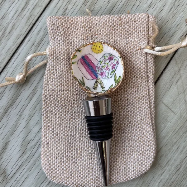A wine bottle stopper topped with a shell patterned with pickleball paddles.