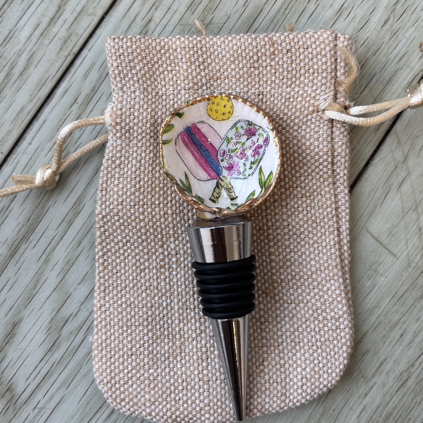 A wine bottle stopper topped with a shell patterned with pickleball paddles.