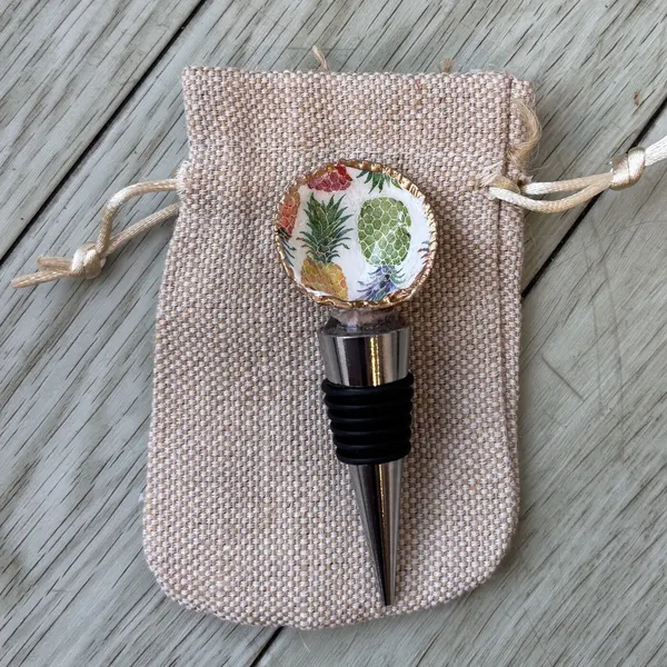 A wine bottle stopper topped with a shell in a pineapple pattern.