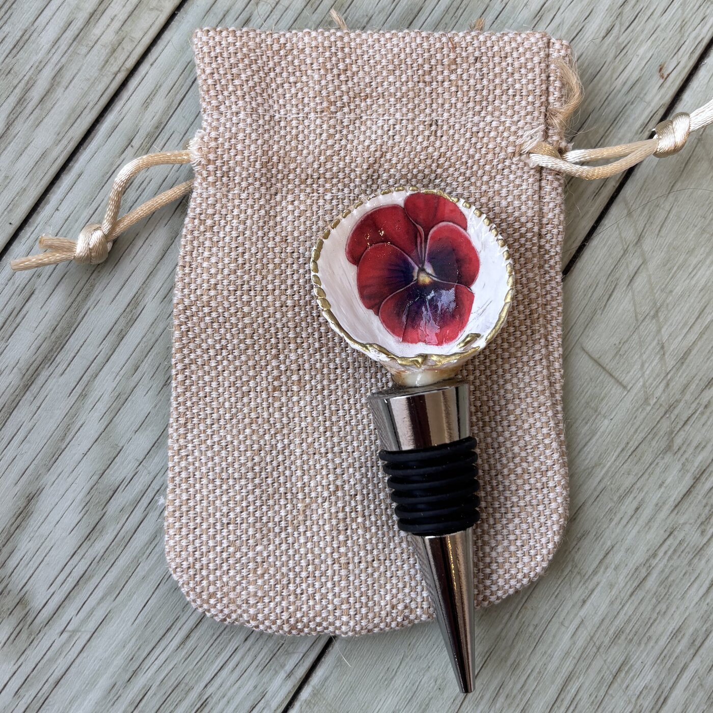 A wine bottle stopper topped with a red pansy shell.